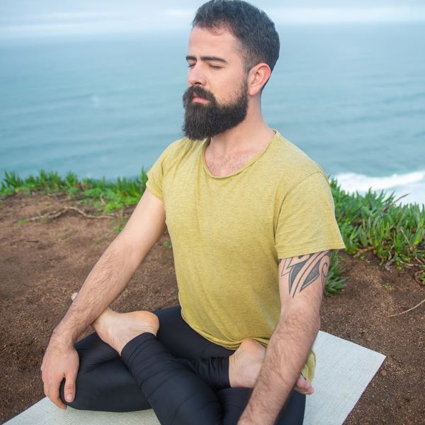 Man sitting in a cross-legged position with eyes closed, meditating.